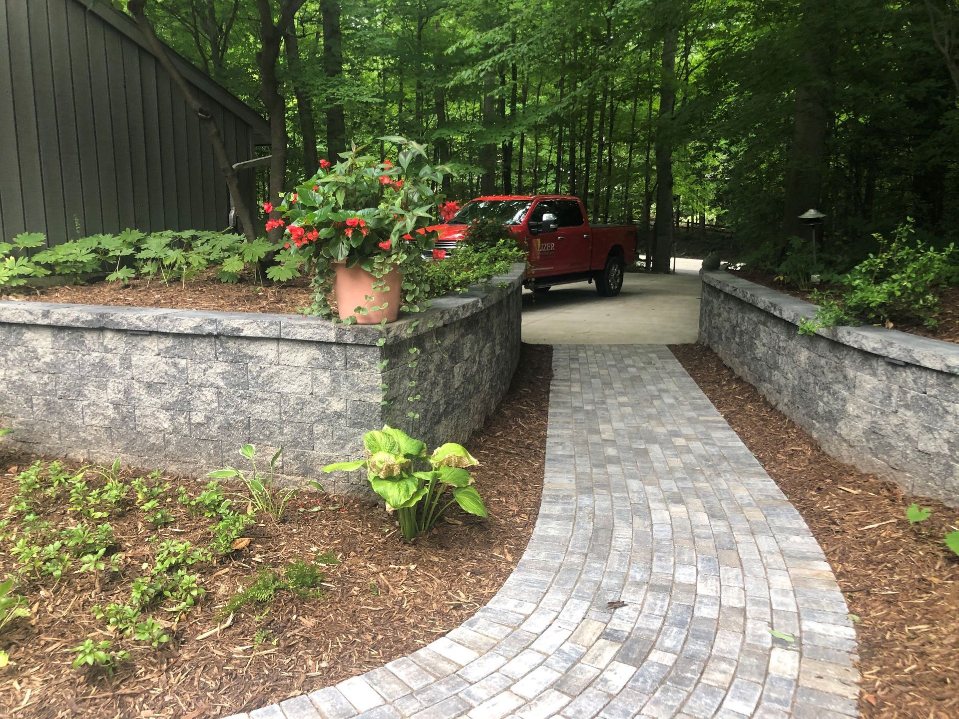 A red truck is parked in a driveway next to a brick walkway