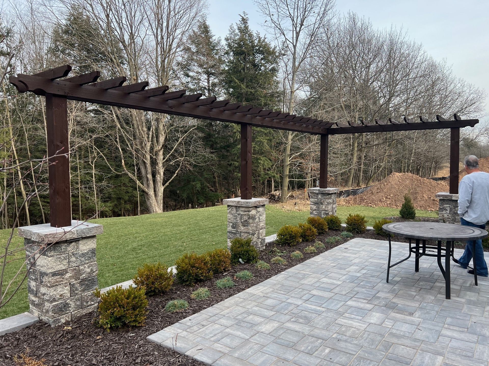 A man is standing under a pergola on a patio