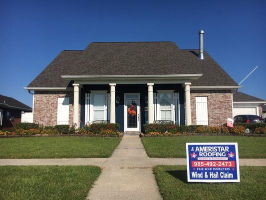 A house with a new roof; a sign for Ameristar Roofing in the front yard; blue sky.