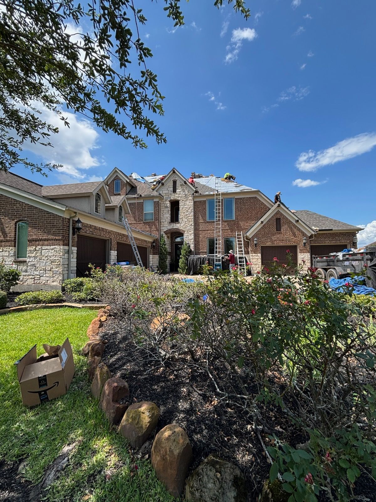 House under construction, roof partially removed. Blue sky, green lawn.