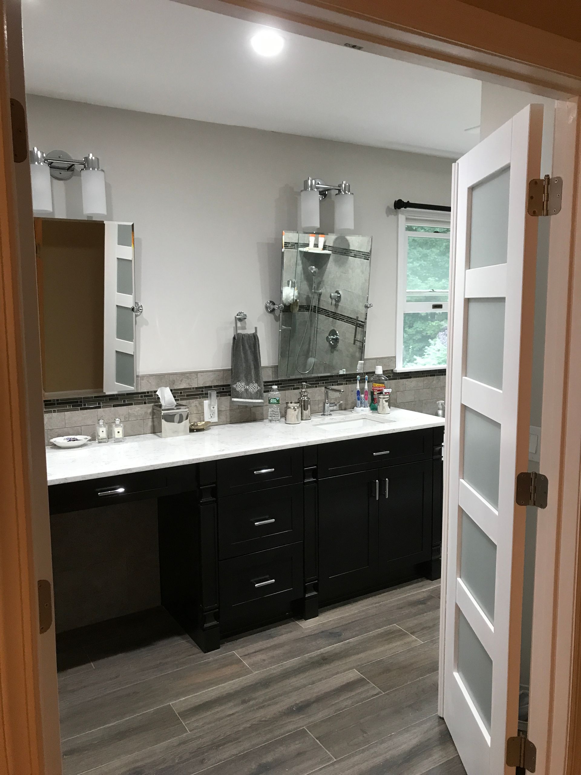 Bathroom with double sink vanity, large mirror, and open door, viewed from the doorway.