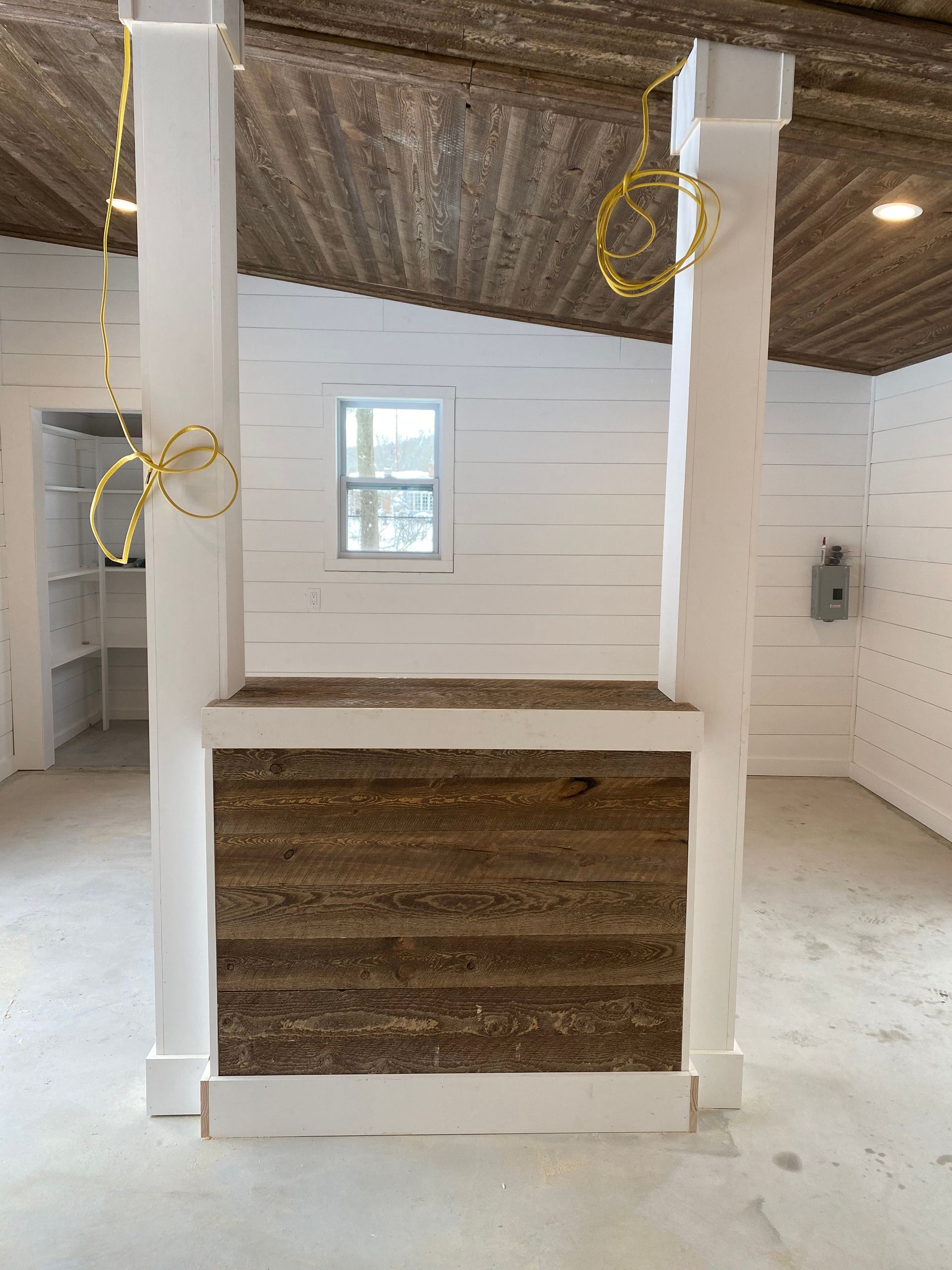 Rustic white stall interior with wood walls, a window, and hanging yellow cord loops.