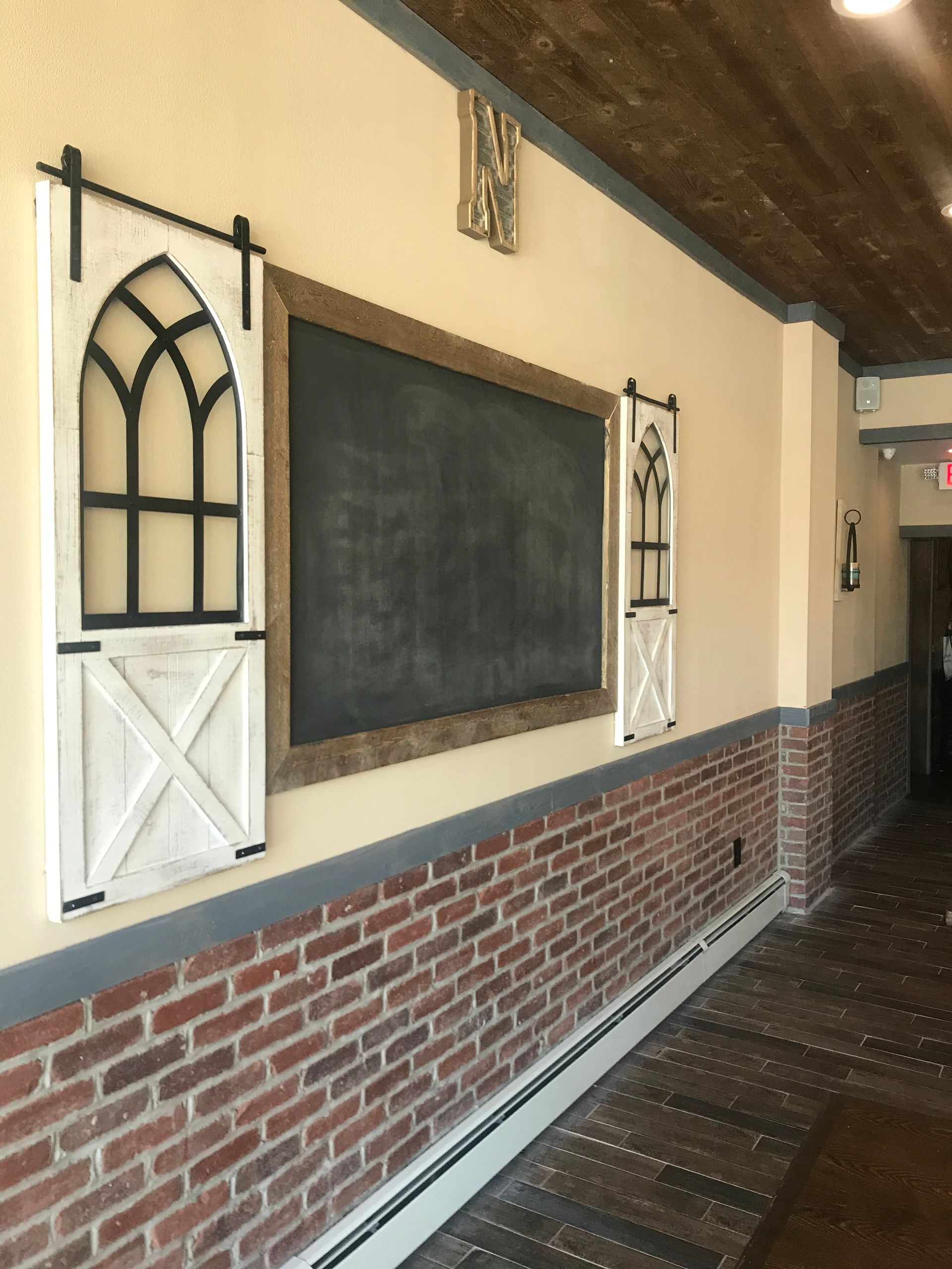 Empty classroom hallway with a chalkboard, brick wainscoting, and decorative wall panels