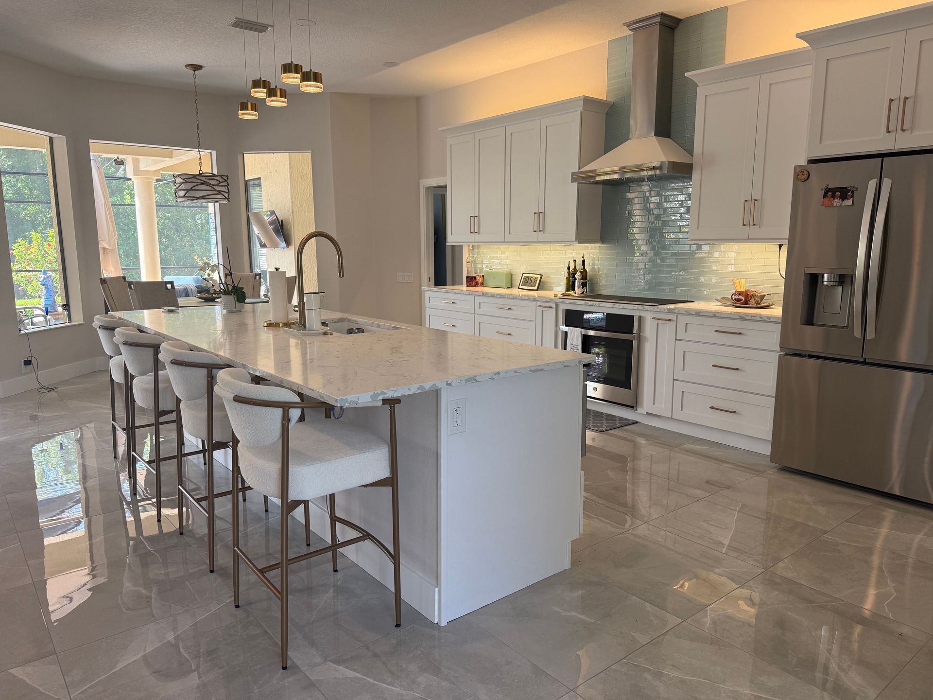 Modern kitchen with white cabinets, marble island, stainless appliances, and pendant lighting