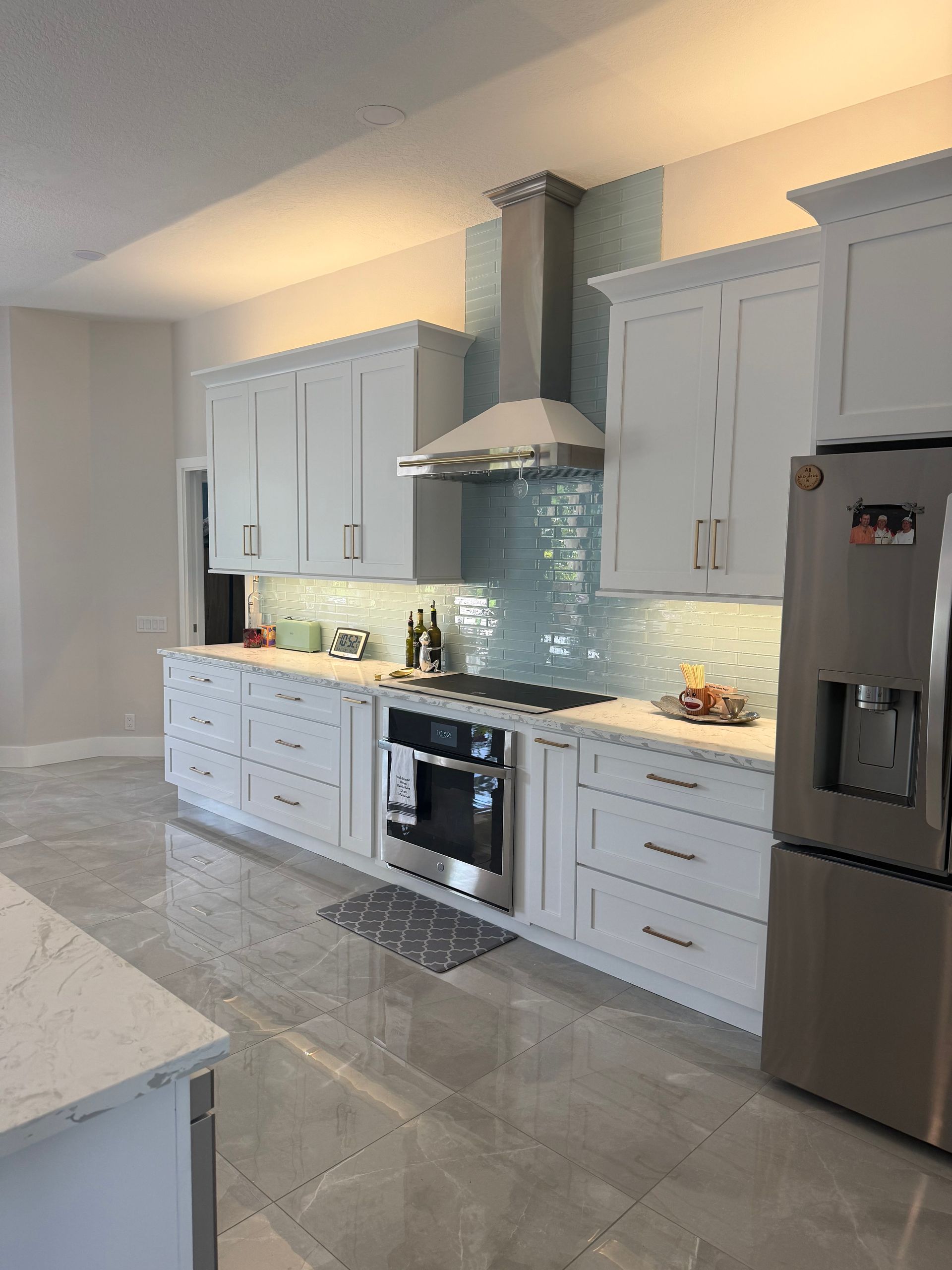 Modern kitchen with gray cabinets, white countertops, blue tile backsplash, and stainless steel appliances
