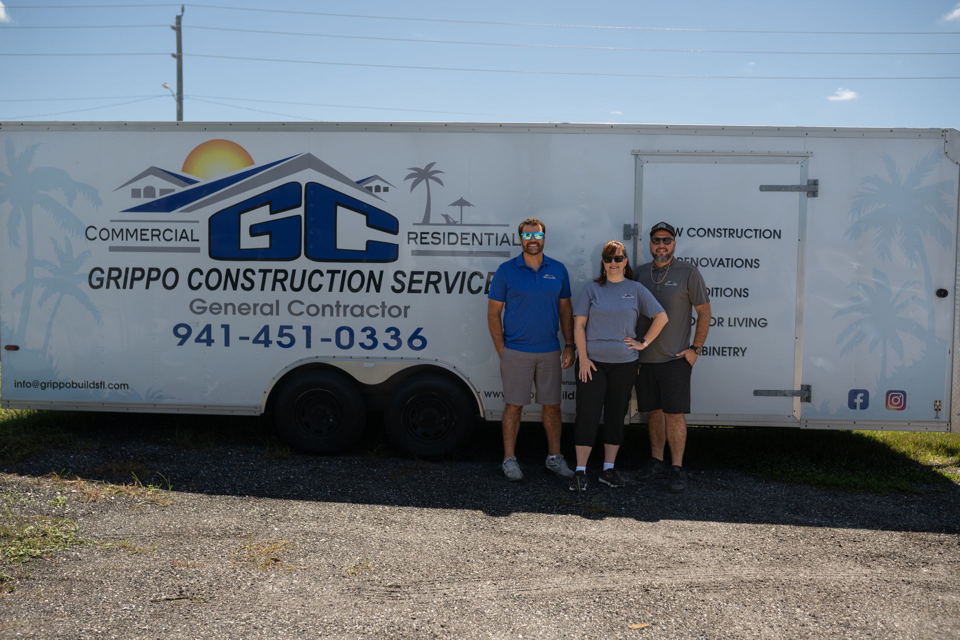 Three people posing in front of a Grippco Construction Service trailer with logo and phone number.