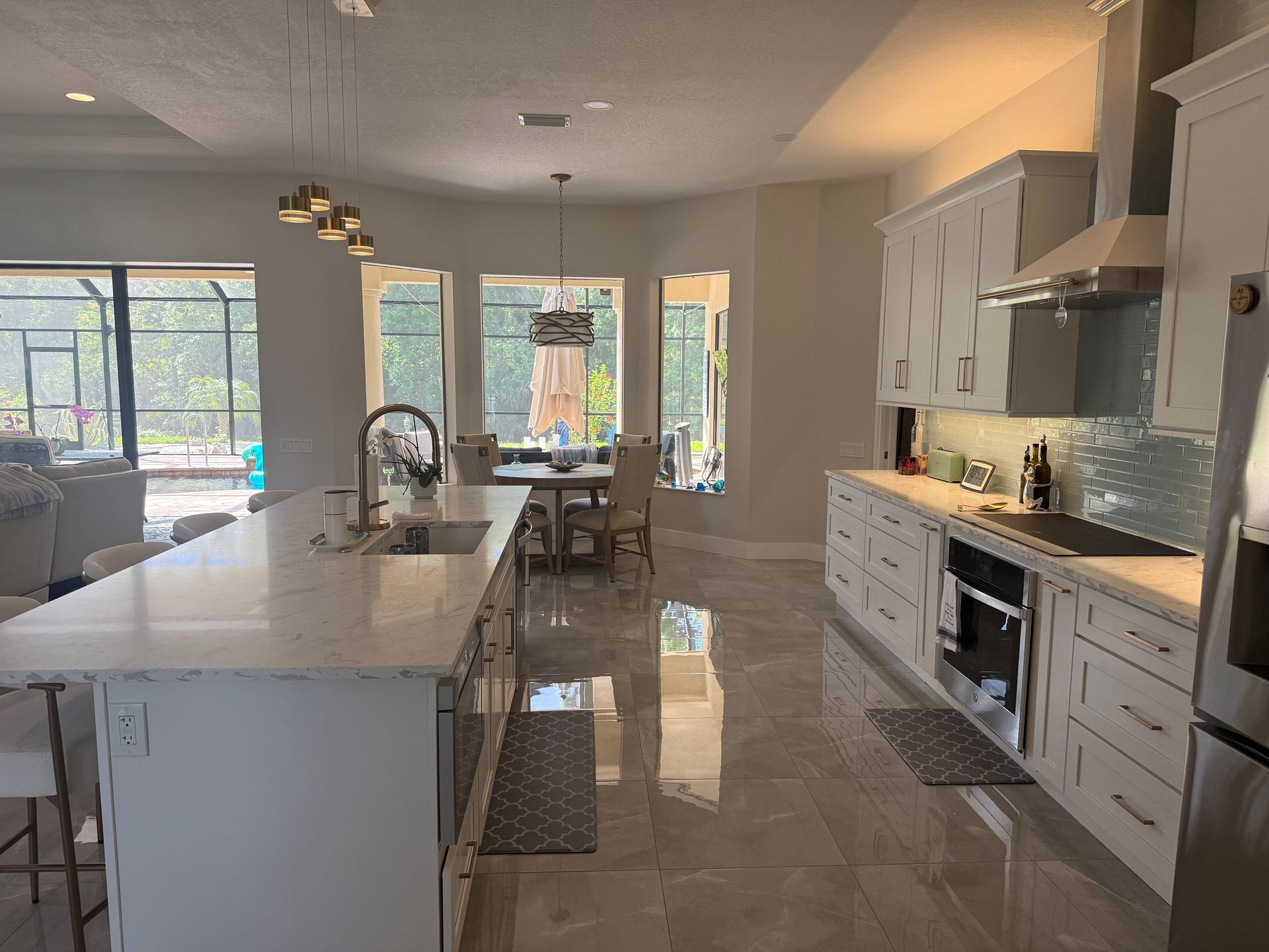 Bright modern kitchen with island, white cabinets, and large windows opening to a dining area
