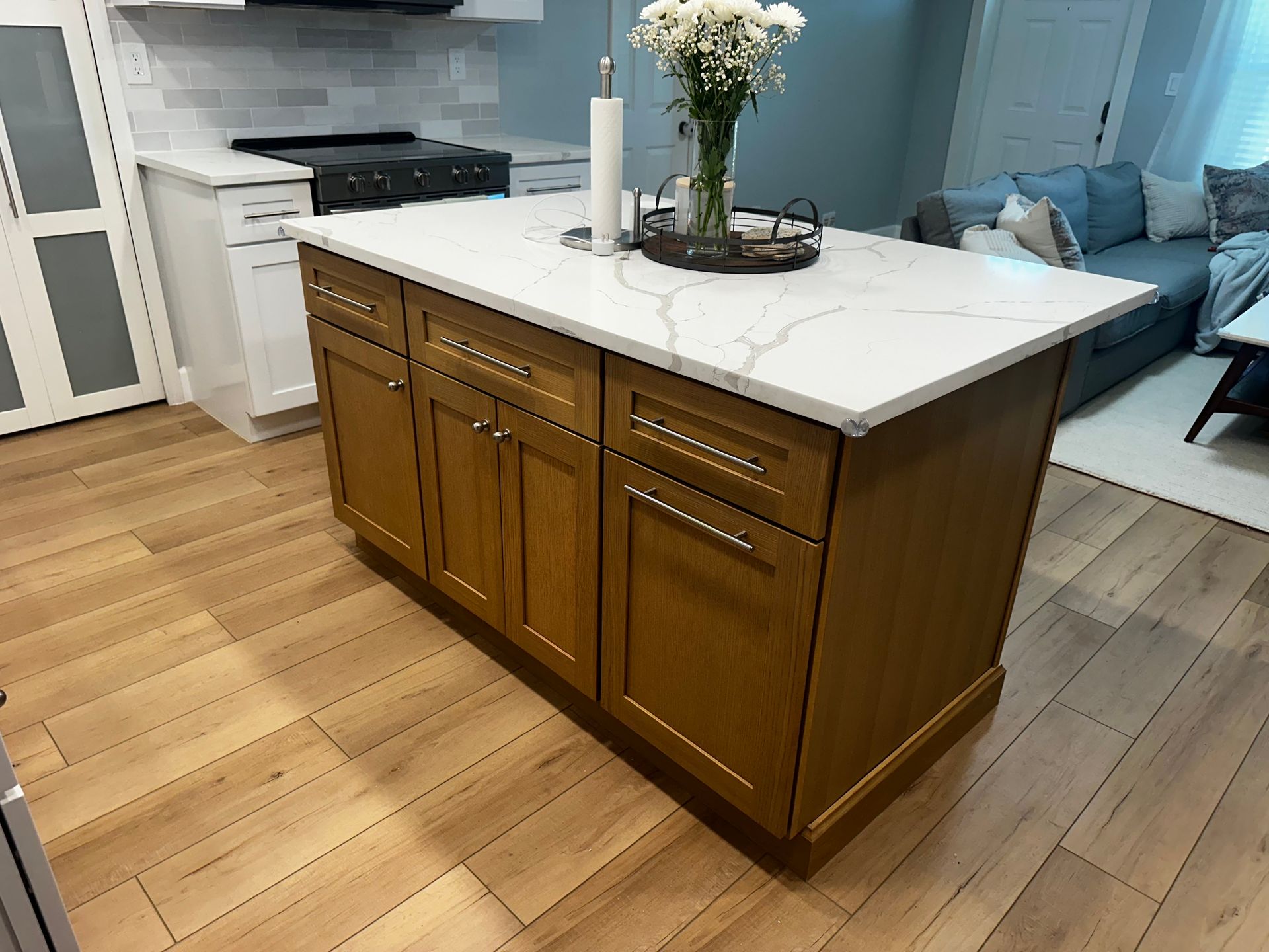 Kitchen island with wood cabinets and white countertop in a bright open-plan living space