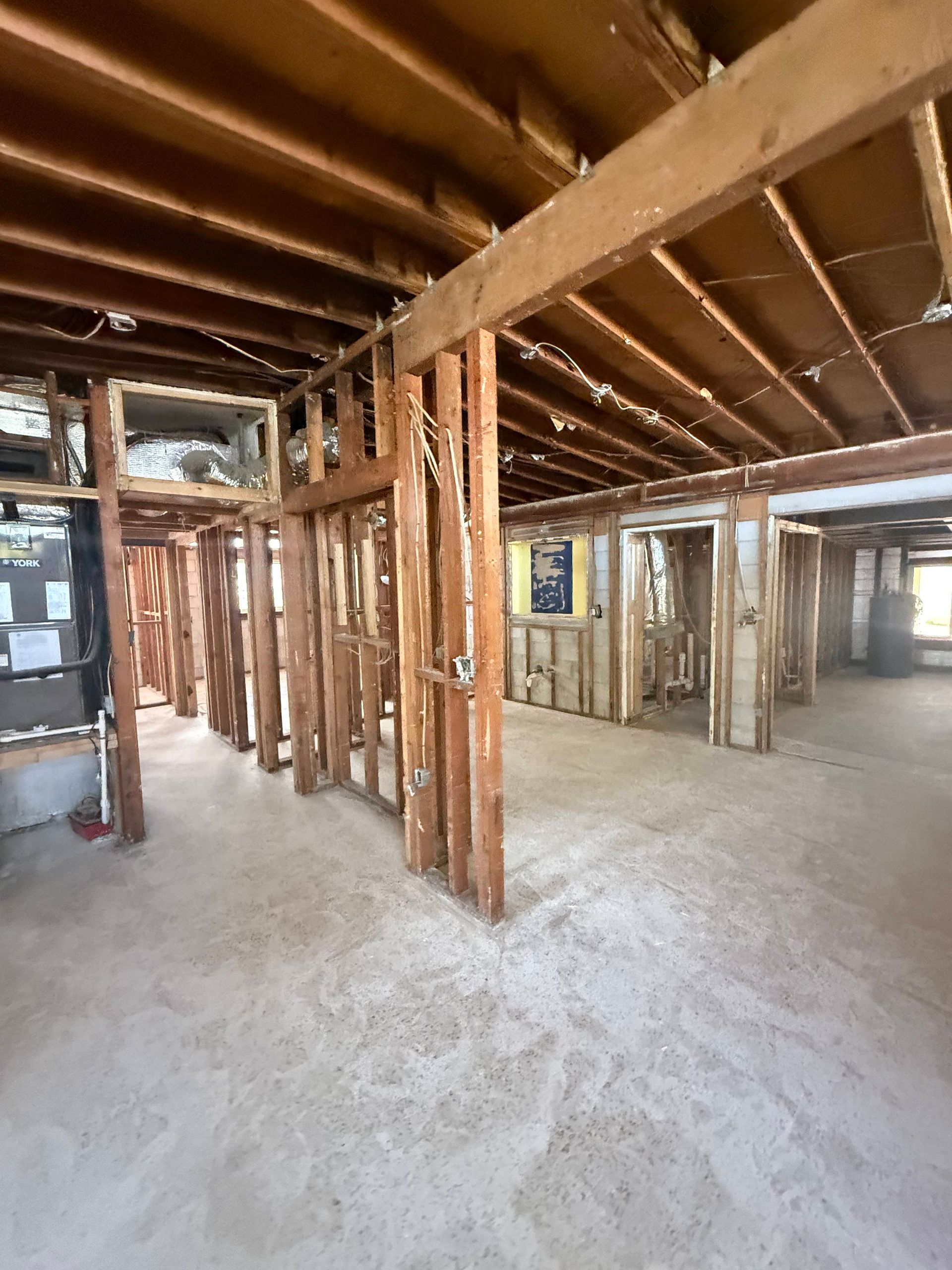 Unfinished basement with exposed wooden beams, support posts, and a concrete floor.