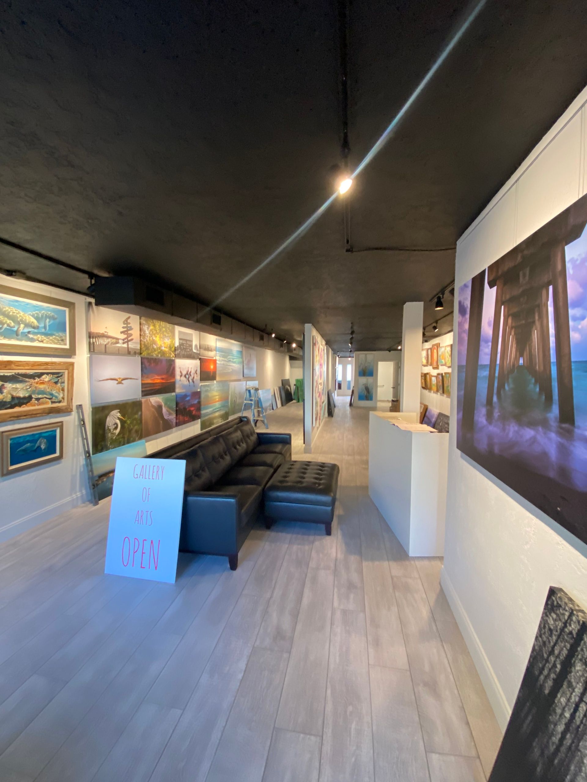Modern art gallery interior with framed paintings, couches, and a large colorful wall display