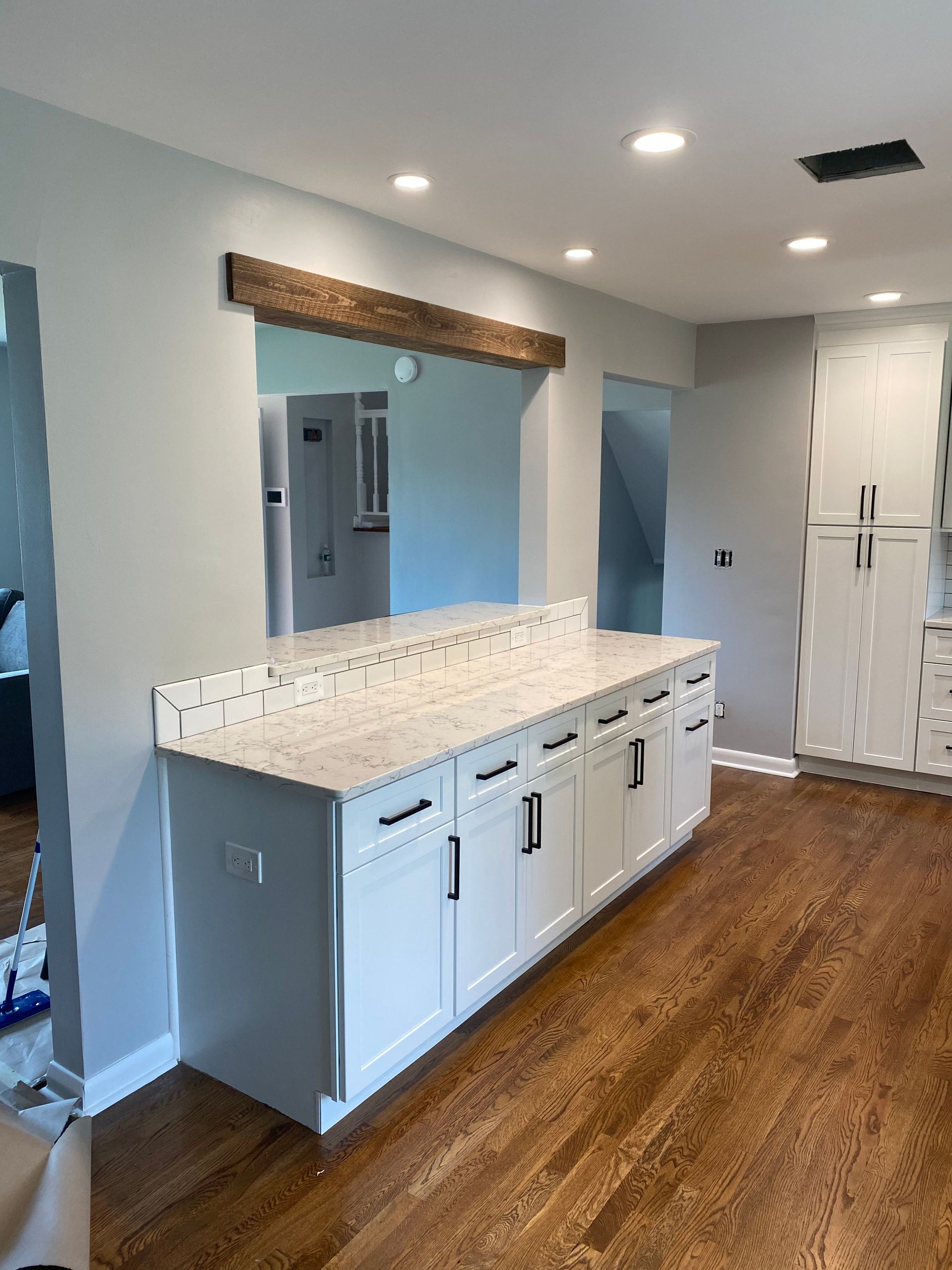Bright kitchen with white cabinets, granite countertop, wood floors, and stainless steel refrigerator.