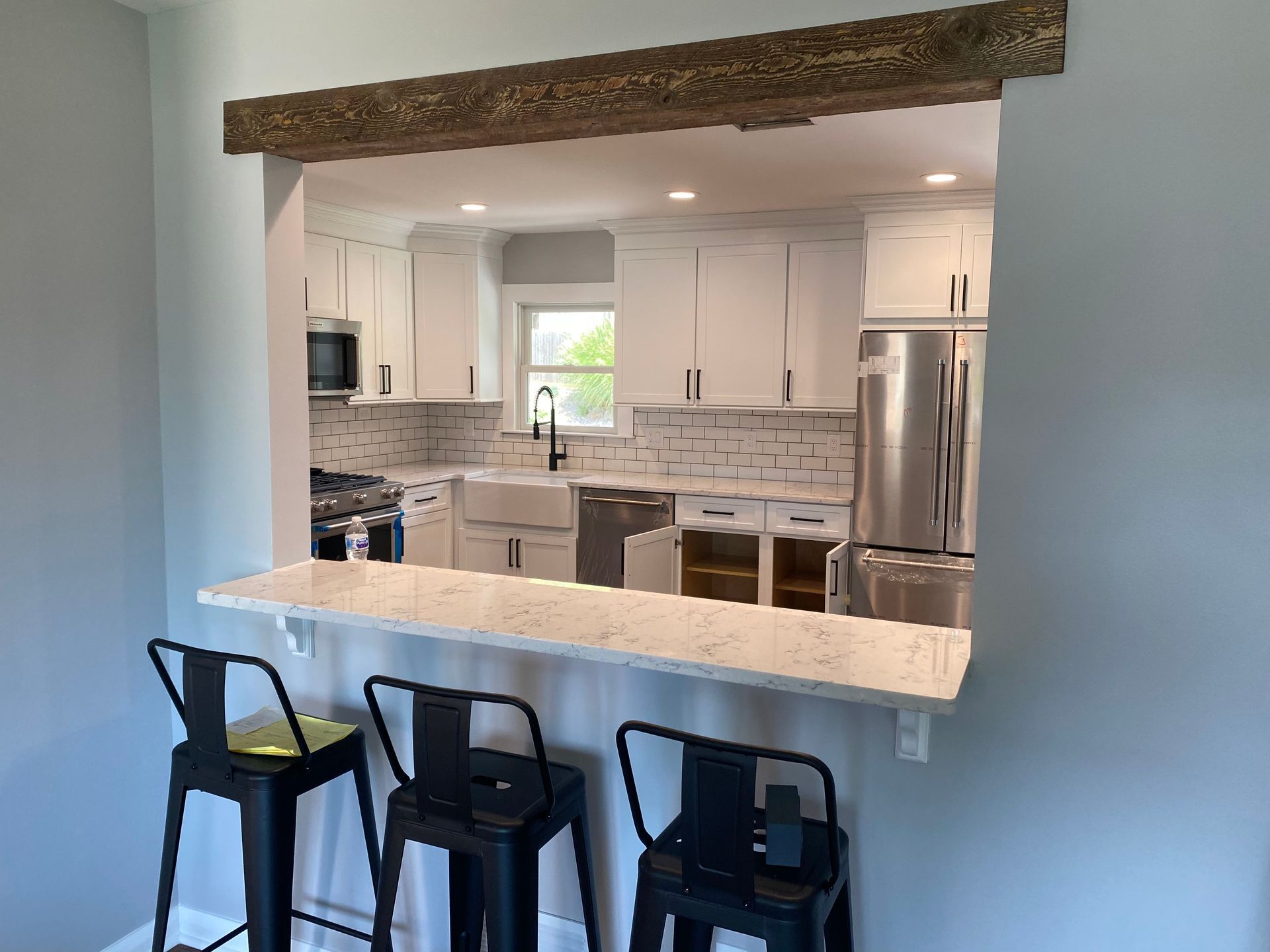 Open kitchen with white cabinets, stainless appliances, and a breakfast bar with black stools