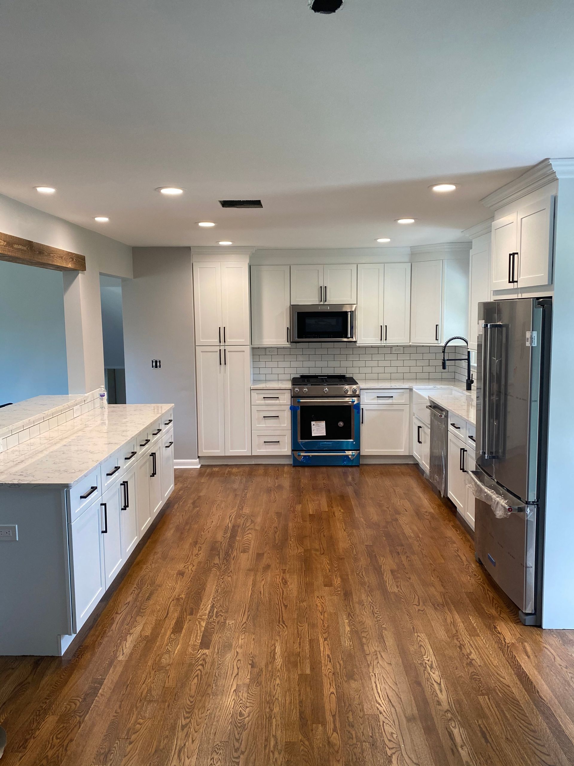 Bright modern kitchen with white cabinets, stainless appliances, and wood floors