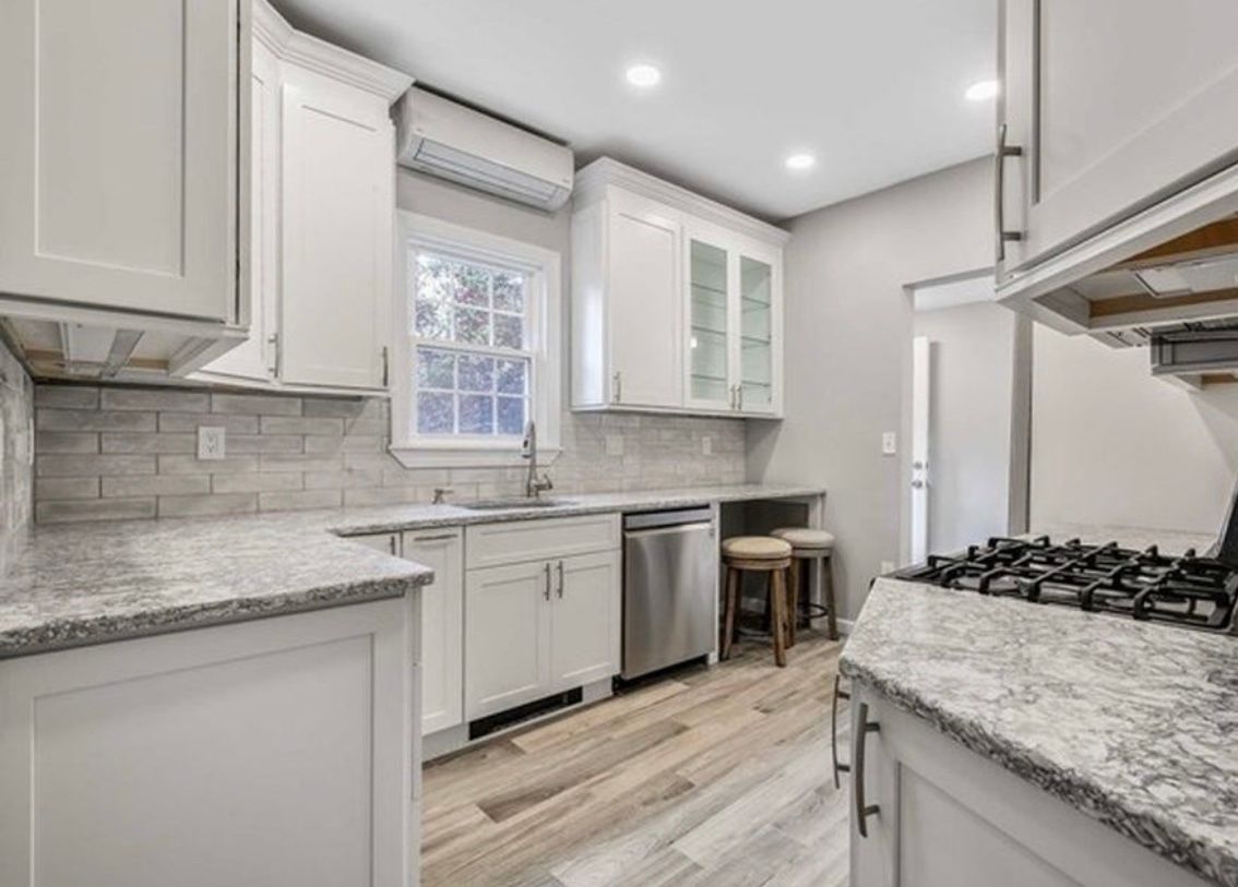 Bright modern kitchen with white cabinets, granite counters, stainless appliances, and a window above the sink