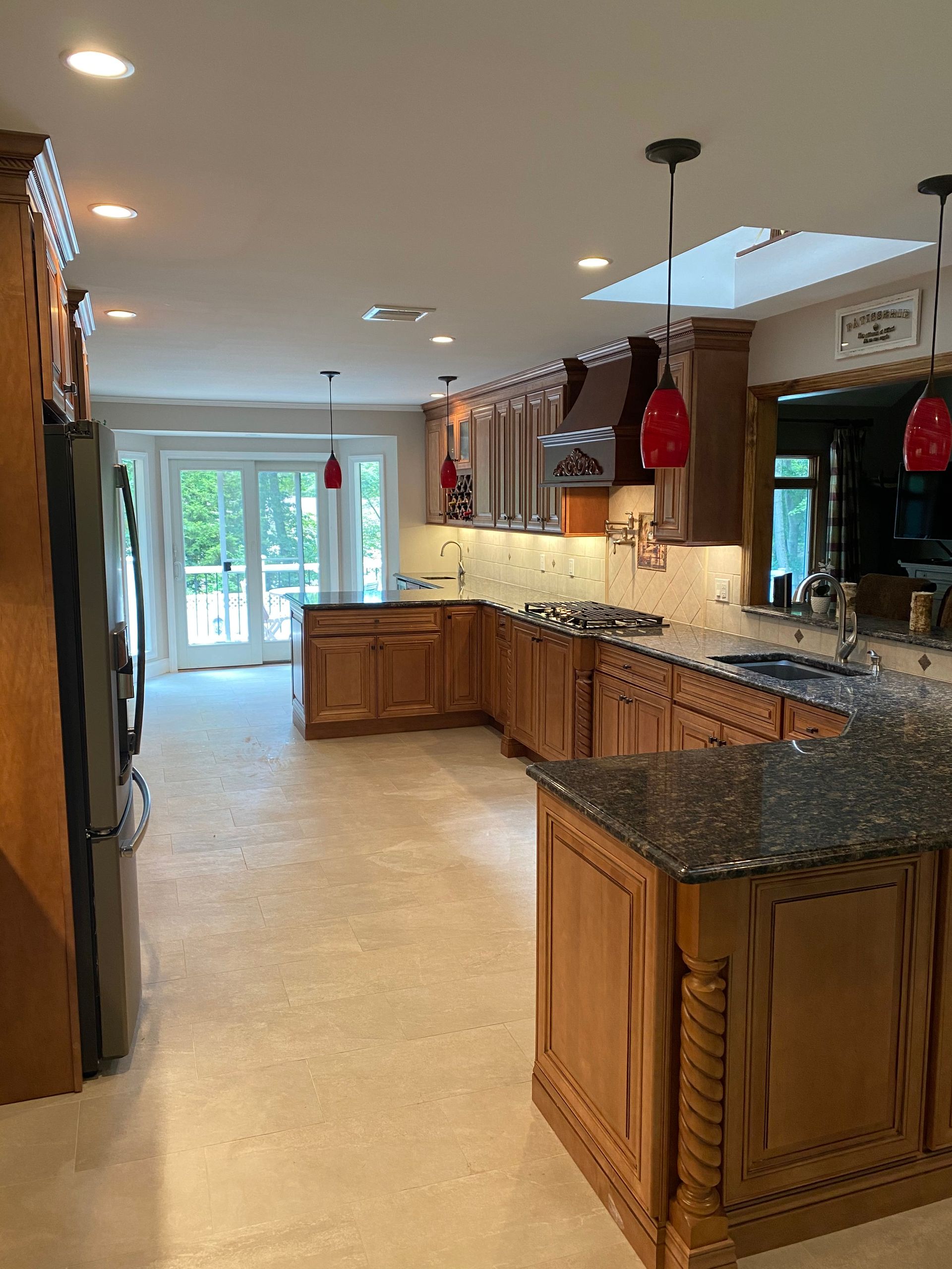 Spacious kitchen with wood cabinets, granite counters, tile floor, and sliding glass doors to a bright patio.