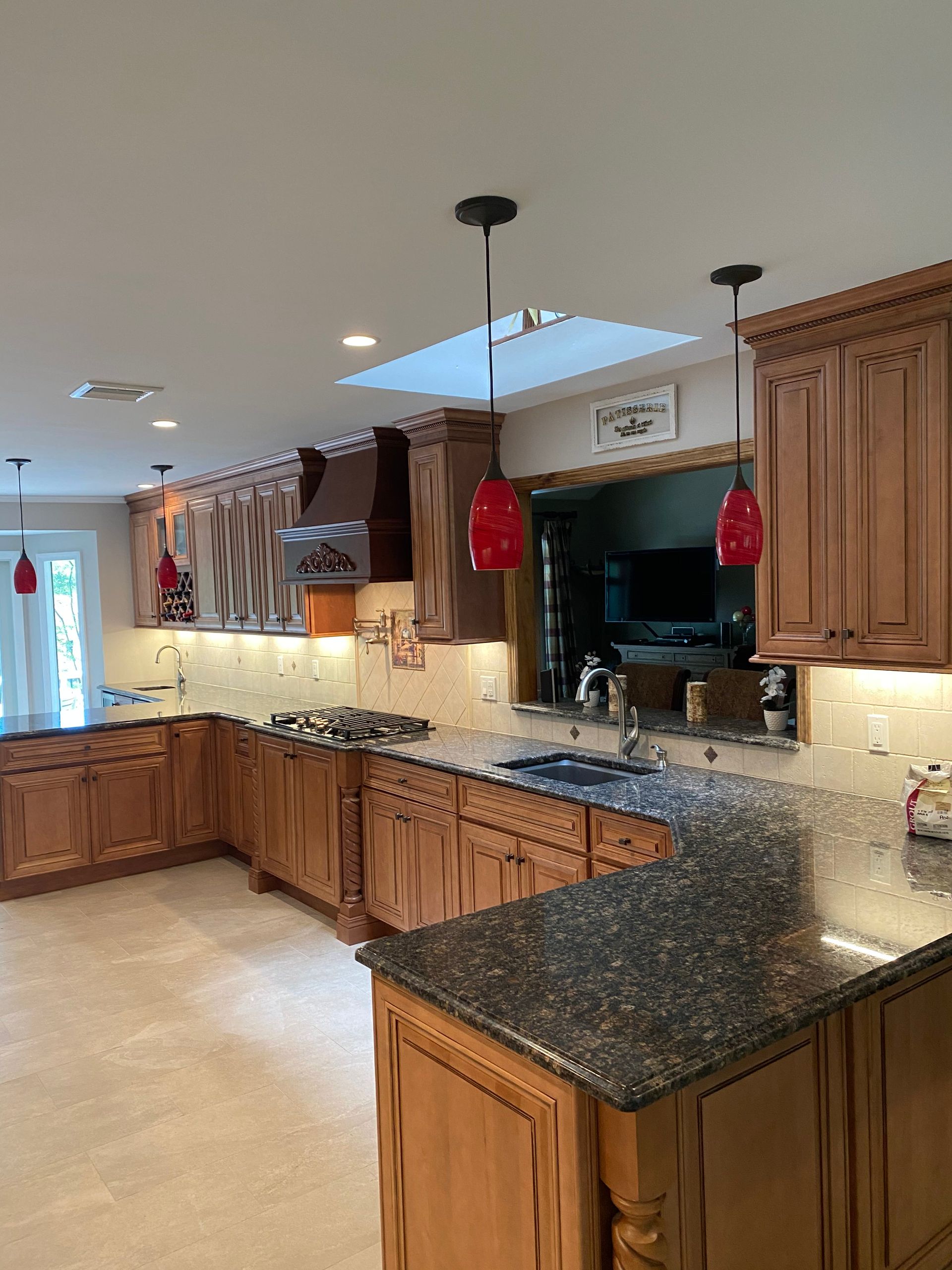 Spacious kitchen with wood cabinets, granite countertops, and stainless appliances under pendant lights