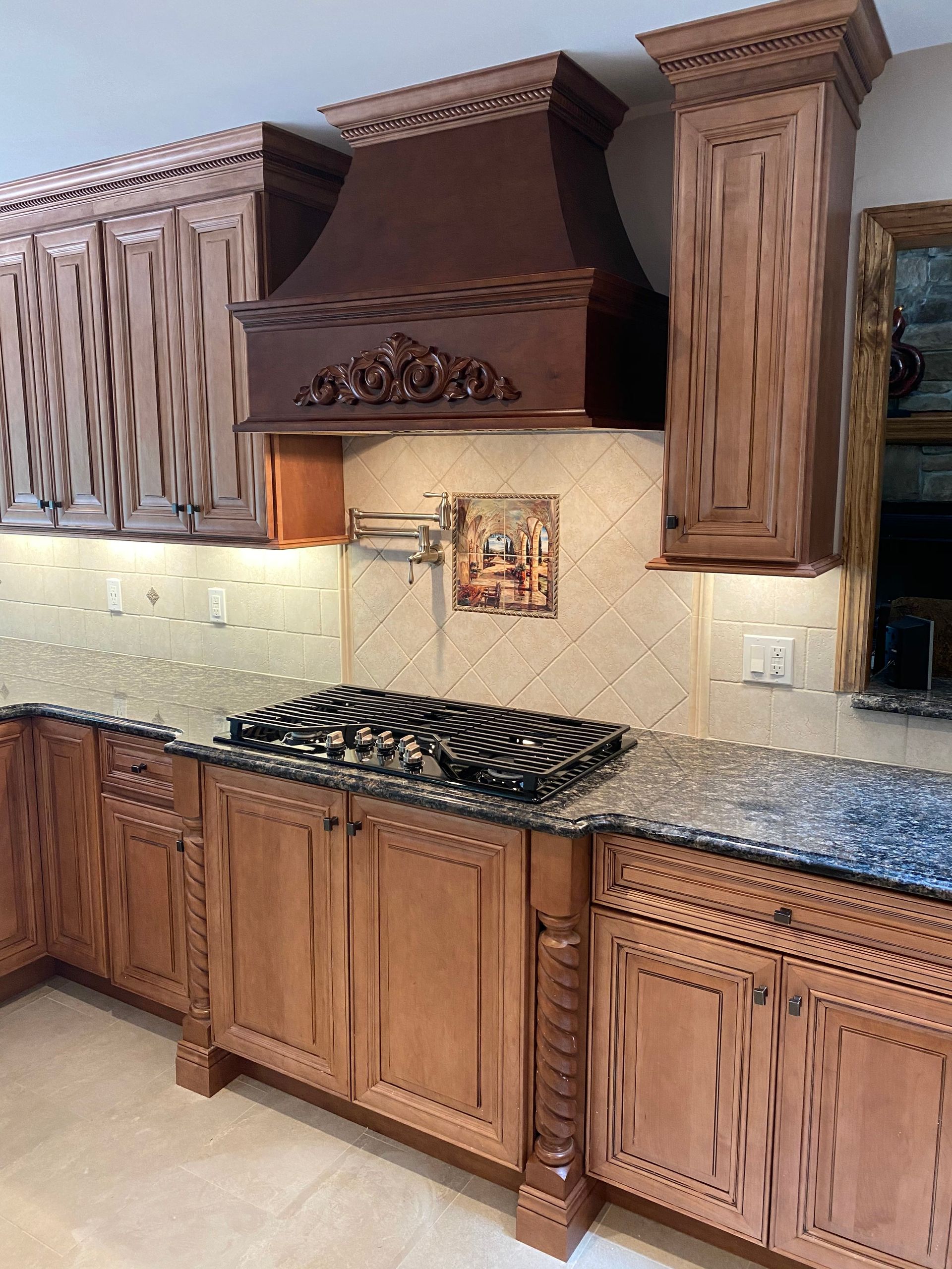 Traditional kitchen with wooden cabinets, granite countertop, and a decorative range hood above the stove