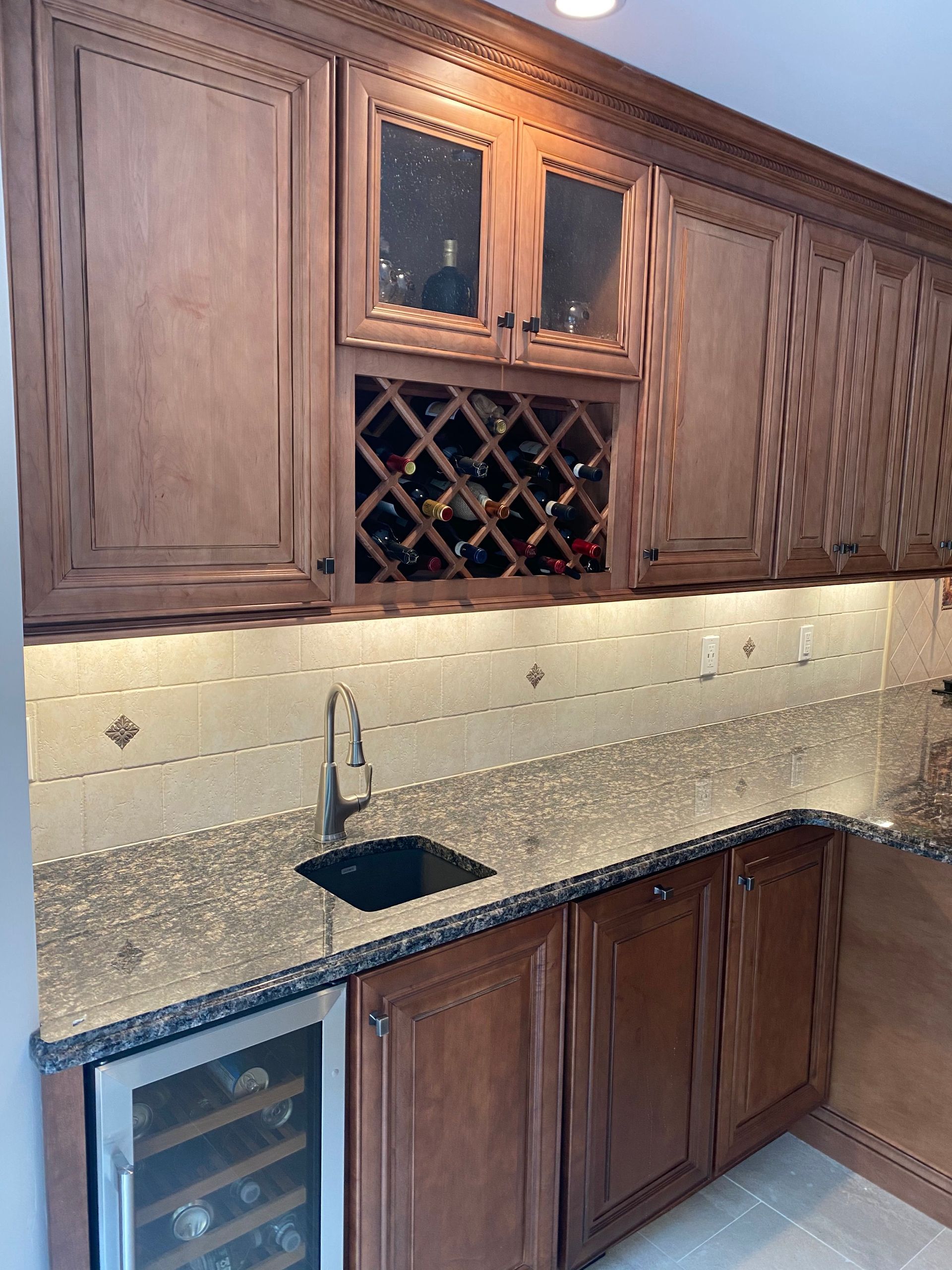 Wooden kitchen cabinets with granite countertop, sink, and built-in wine rack