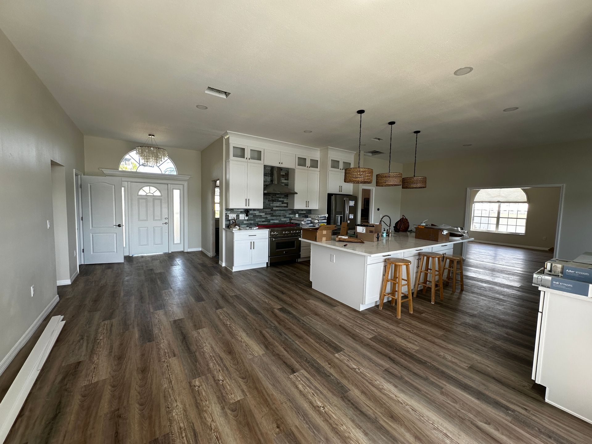 Bright open-plan kitchen and dining area with wood floors, white cabinets, and an island with stools.