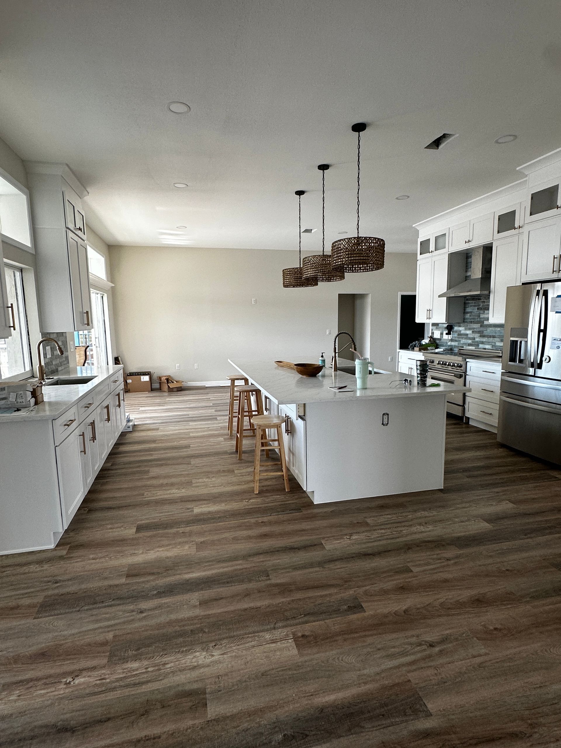 Bright modern kitchen with white cabinets, island, stools, and wood-look flooring