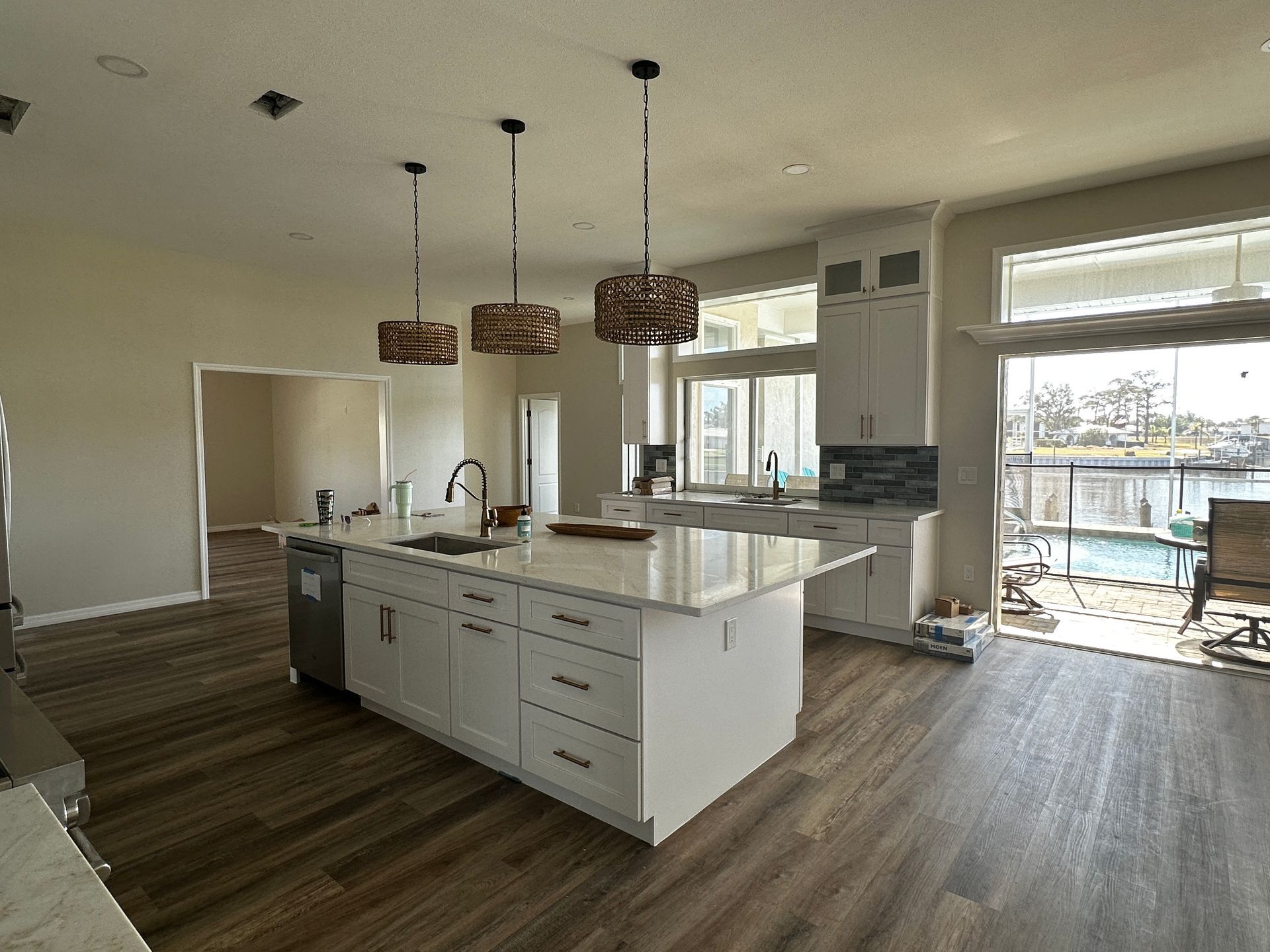 Modern open-plan kitchen with white island, hanging pendant lights, and sliding doors to a patio.