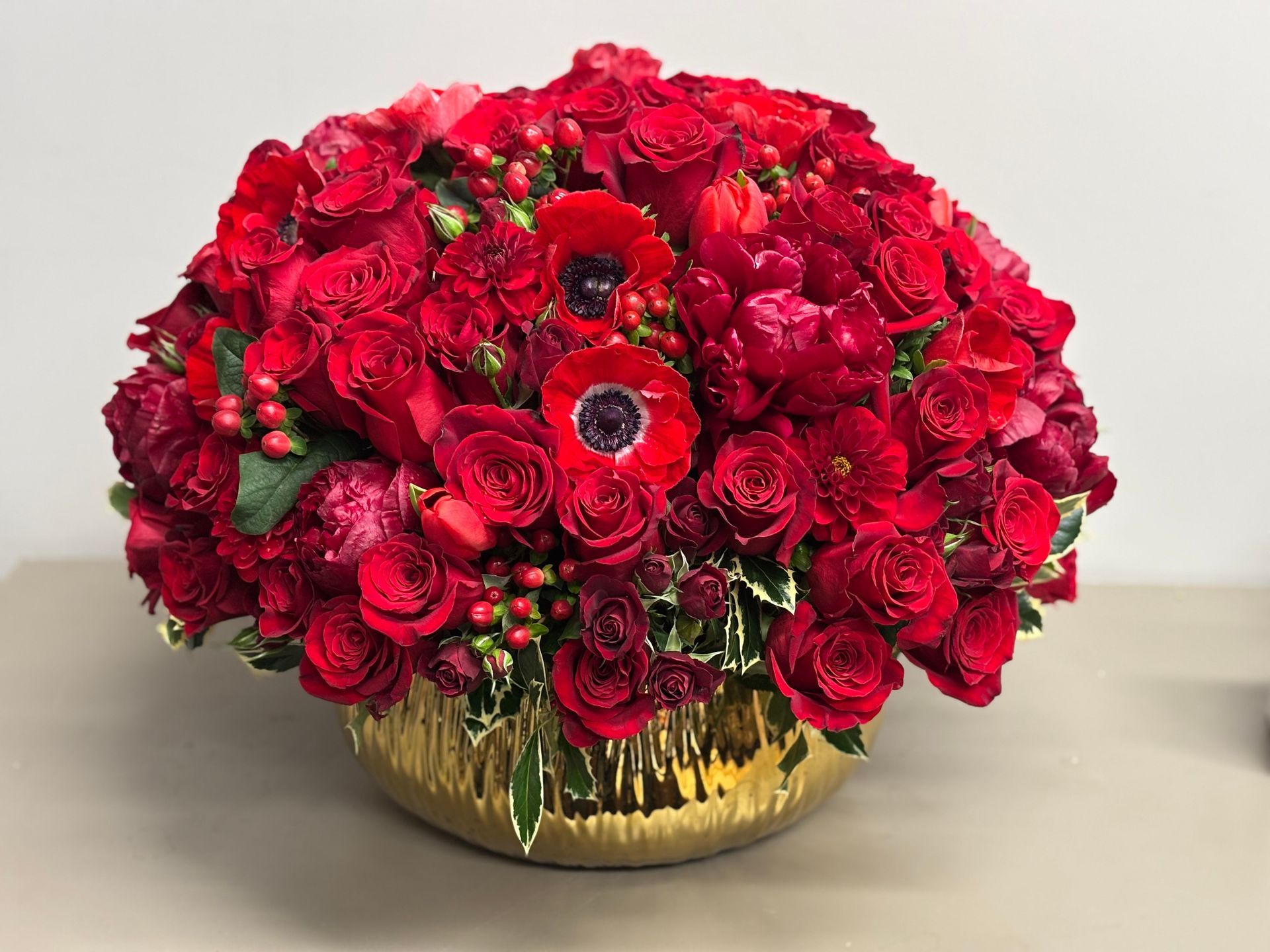 Red rose arrangement in a gold, textured bowl