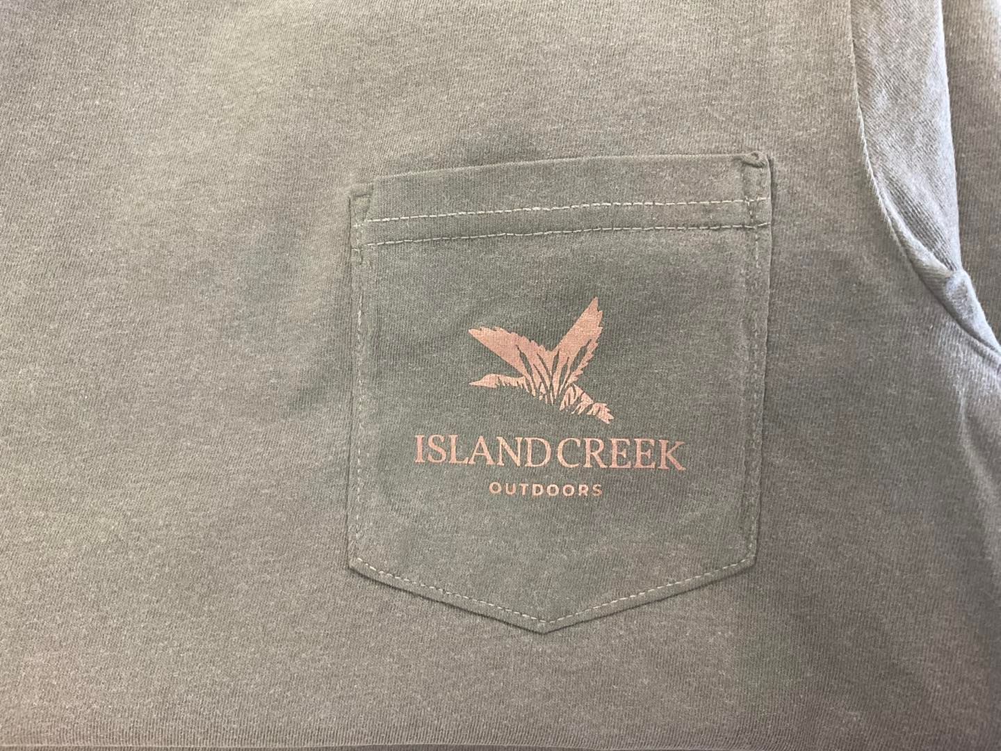 Green shirt pocket with salmon-colored logo: flying bird and 