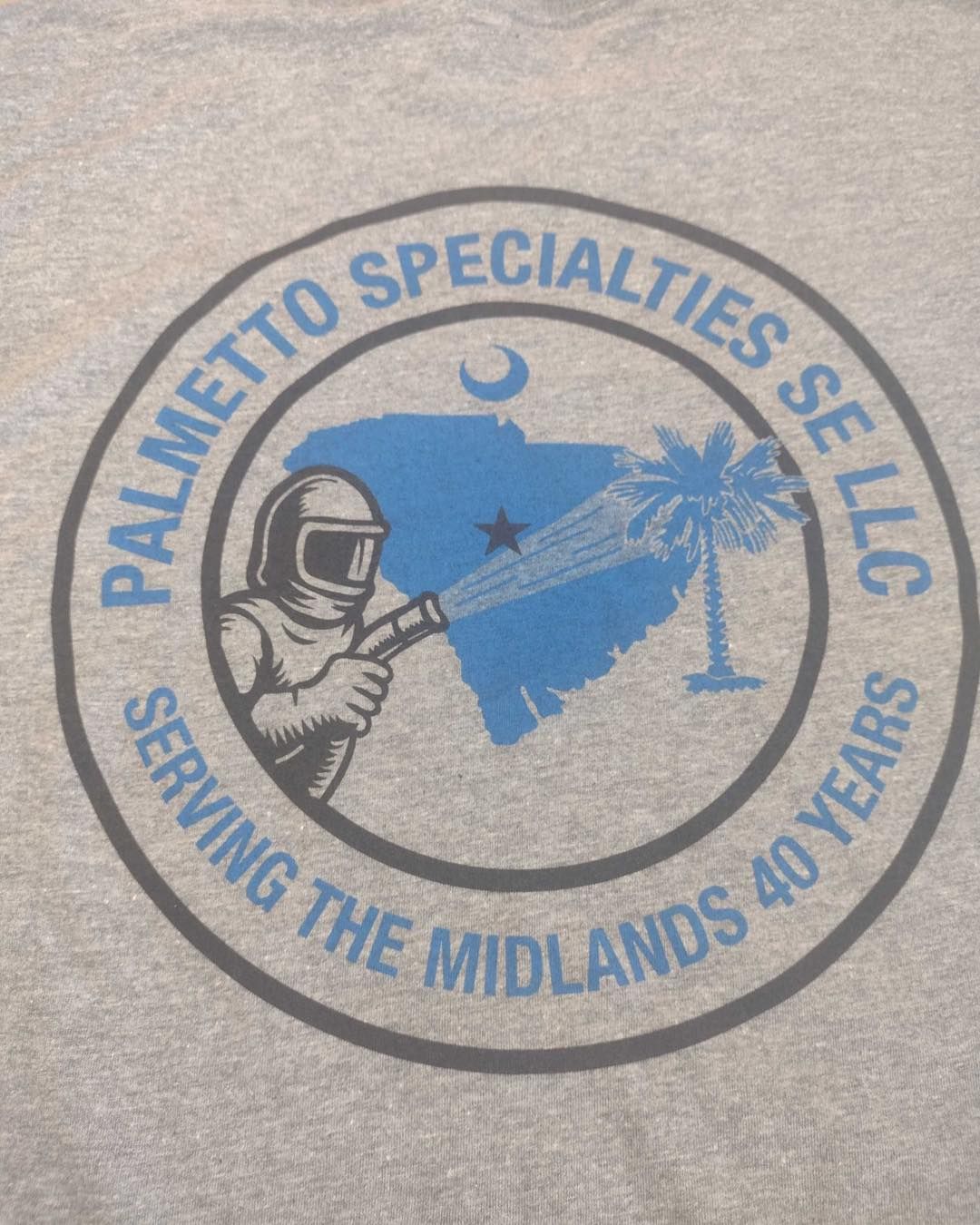 Palmetto Specialties SE LLC logo on grey shirt: SC map, palm tree, worker spraying, text 