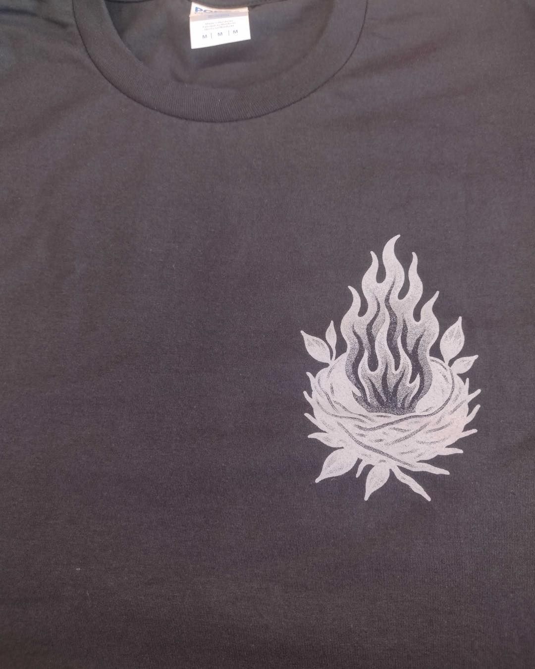 Black t-shirt with a small illustration of a nest engulfed in flames.