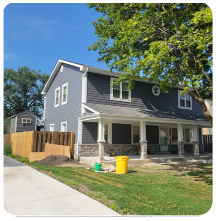 A gray house with a porch and a yellow trash can in front of it