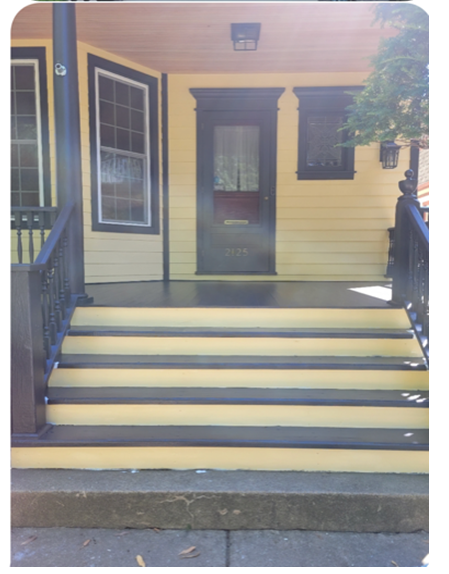 A yellow house with black steps and a black door