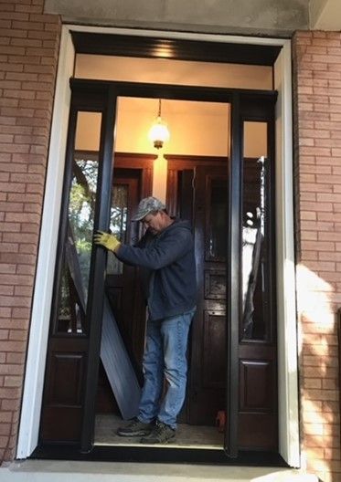 A man is installing a door in a brick building