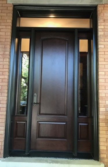 A wooden door with a black trim is on a brick building.