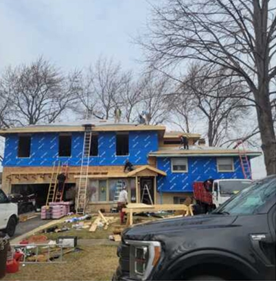 A black truck is parked in front of a house under construction.