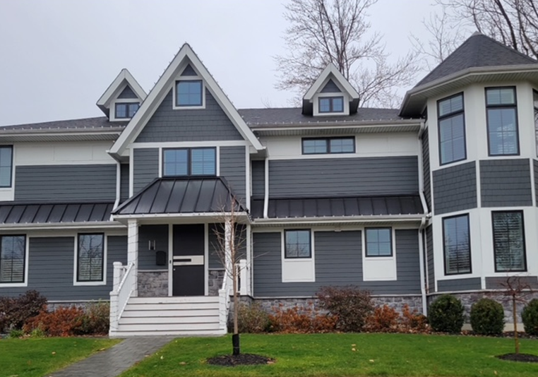 Gray house with white trim, black roof, and manicured lawn.