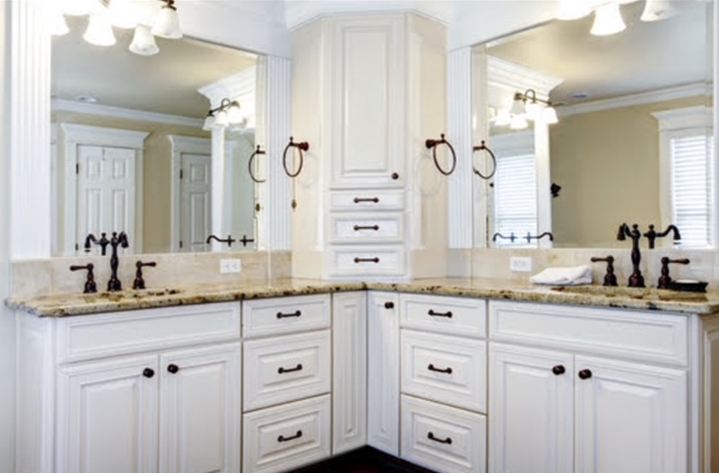 White double bathroom vanity with black hardware, mirrors, and beige countertop.