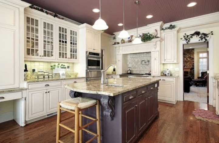 Elegant kitchen with cream cabinets, brown island, granite countertops, and hardwood floors.