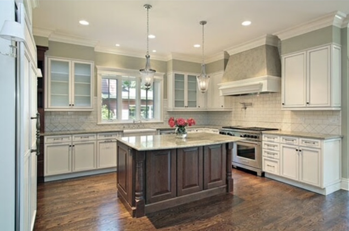 Kitchen with dark wood island and white cabinets. Overhead lights and gas range.