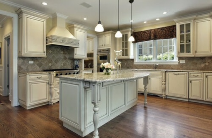 Elegant cream-colored kitchen with island, wooden floors, and a window above the sink.
