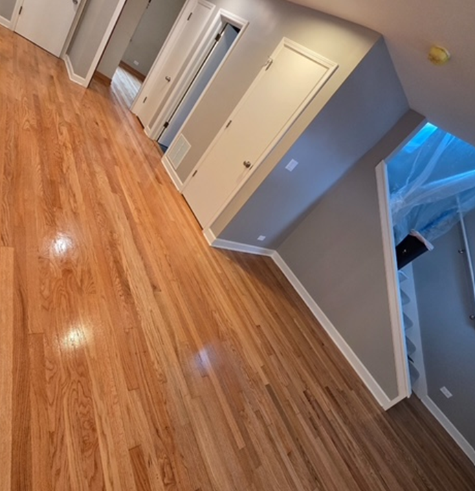 A hallway with hardwood floors and stairs in the background