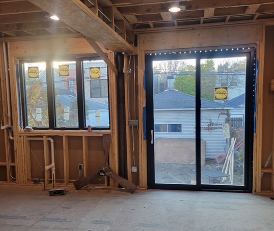 Interior view of a building under construction, showing windows and a sliding door.