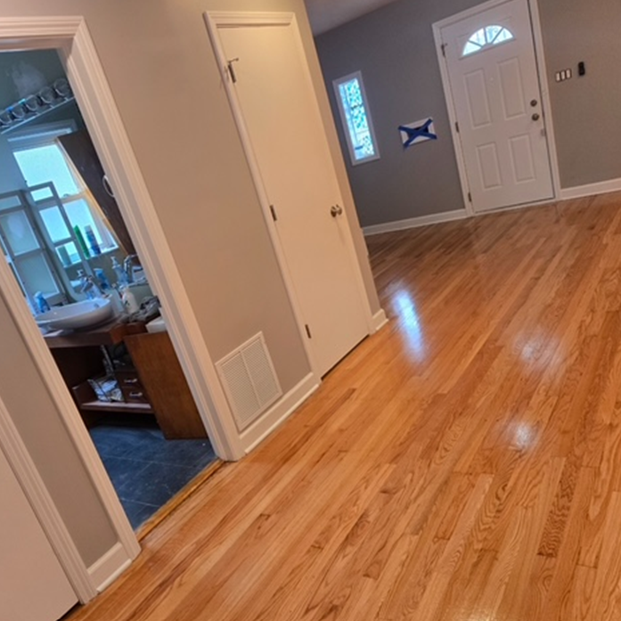 A hallway with hardwood floors leading to a bathroom