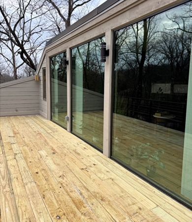 A wooden deck with a lot of windows on a house.