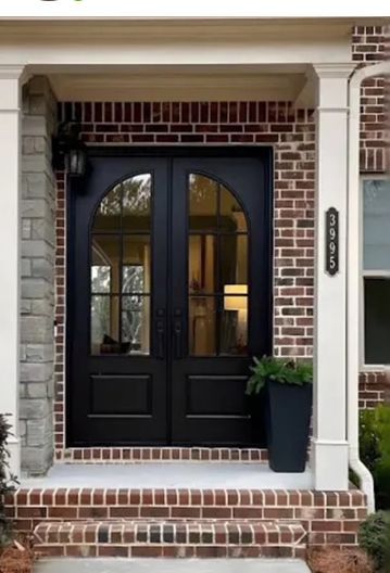 The front door of a brick house with black doors