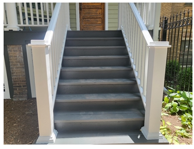 A set of stairs leading up to a porch with a white railing