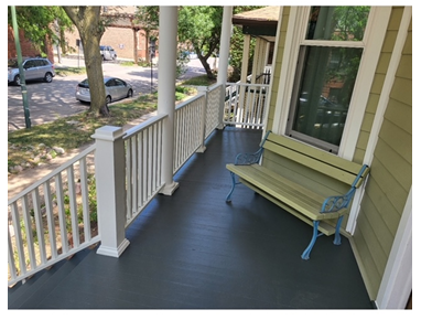 A porch with a bench and a white railing