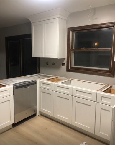 A kitchen with white cabinets and a stainless steel dishwasher.