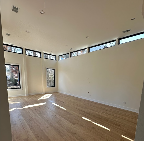 A large empty room with hardwood floors and lots of windows