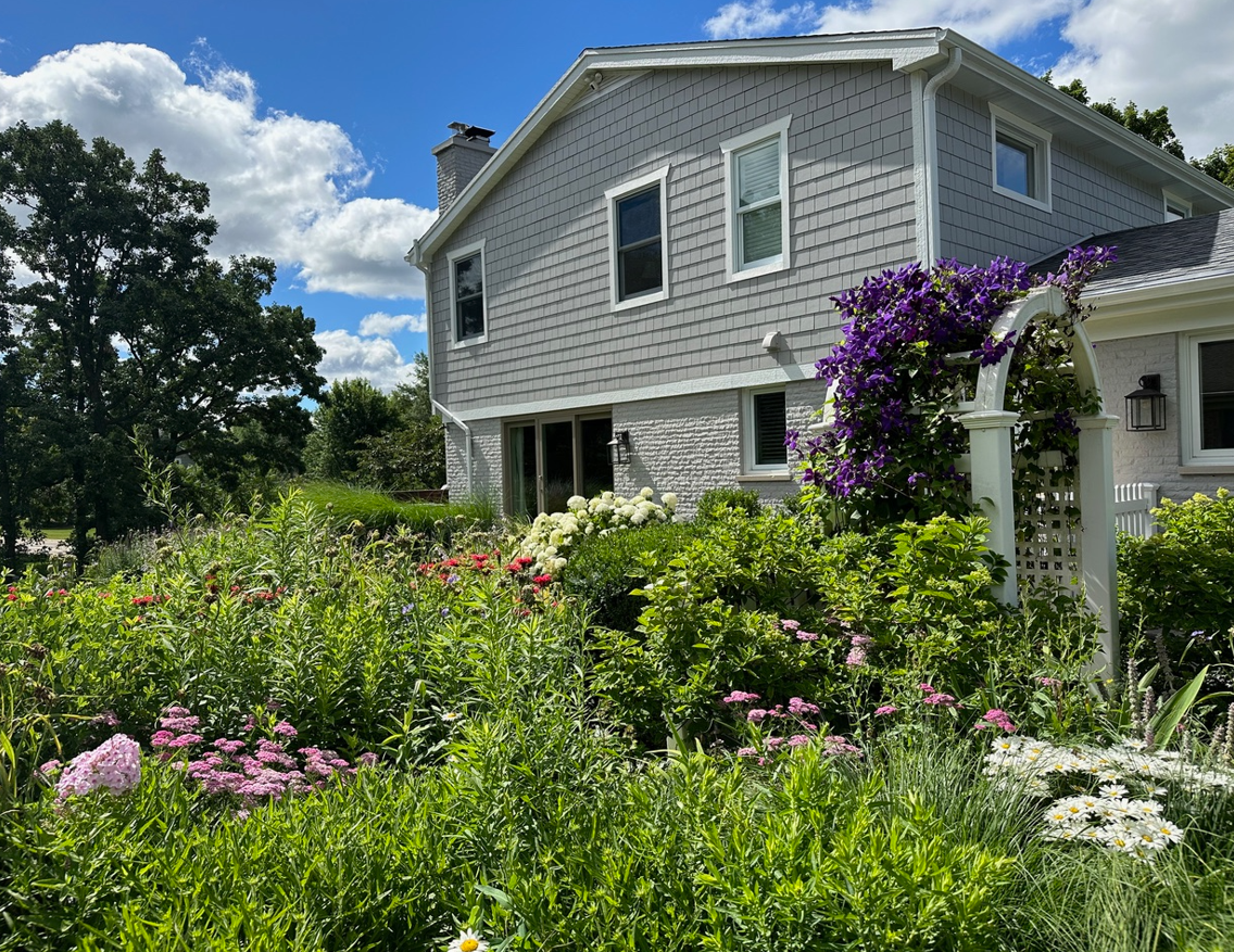 A house with a lot of flowers in front of it.