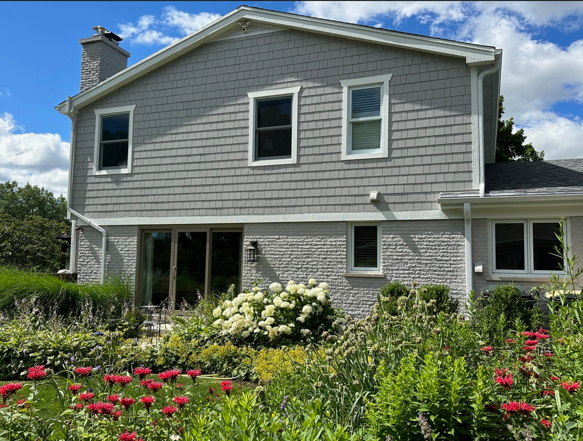 A house with a lot of windows and flowers in front of it.